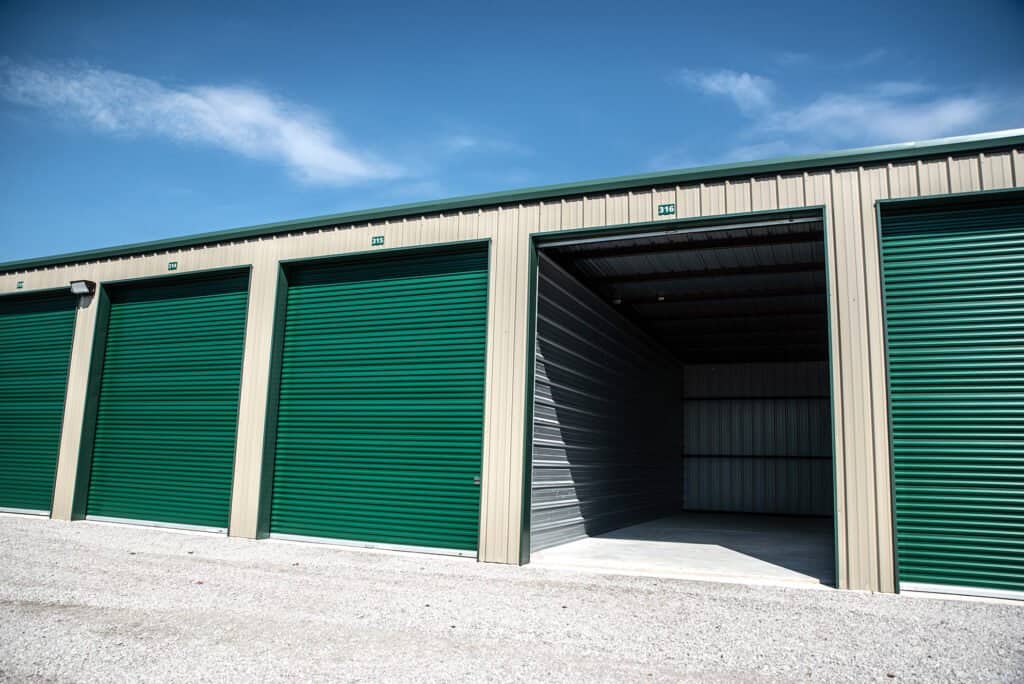 Outdoor shot of wide drive aisles and rows of enclosed parking -with closed green garage doors and one open empty unit