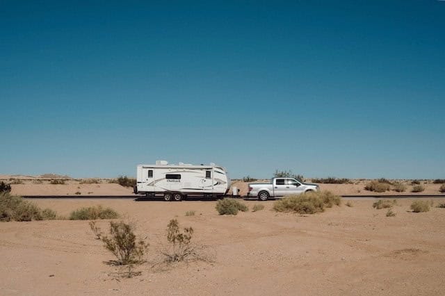 Trailer being pulled by a pickup truck on a highway in a desert landscape