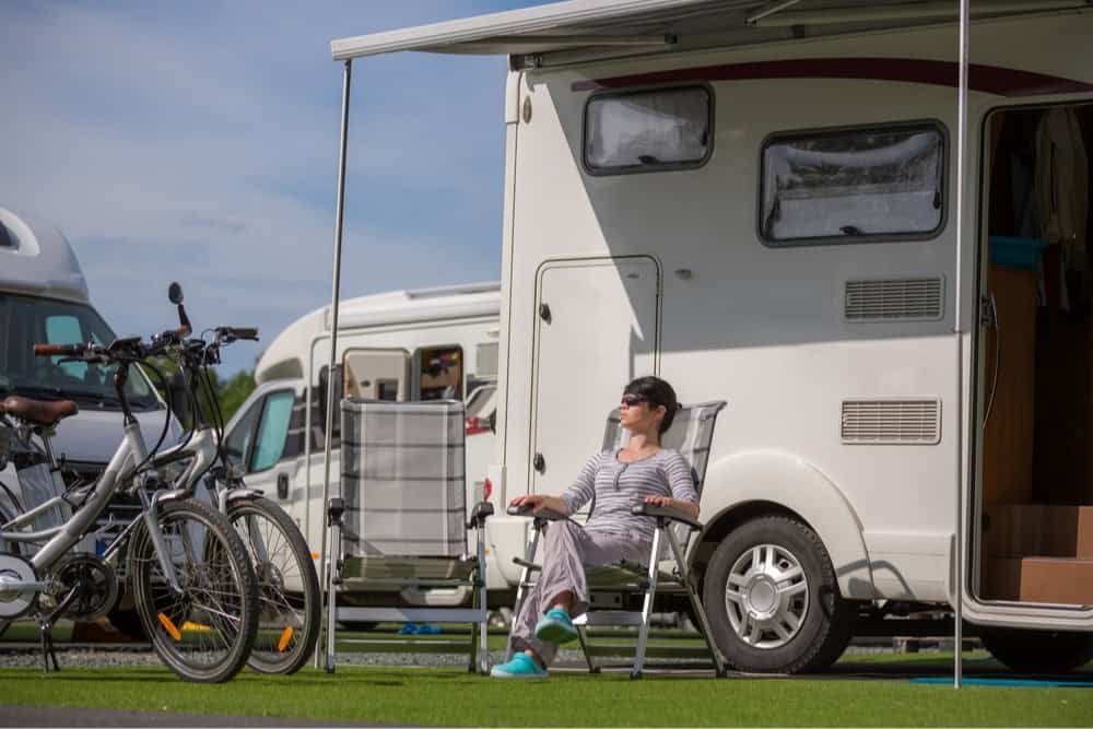 Woman sitting in the sun in a lawn chair in front of her RV