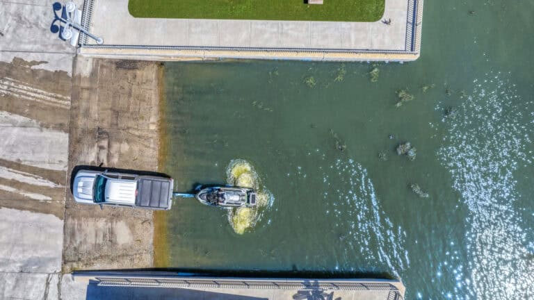 Heavy-duty industrial water pump operating in a large concrete water channel with a truck nearby.