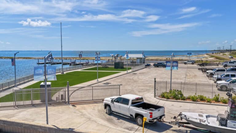 Outrig waterfront boat launch and marina facility on a sunny day with blue sky and water.