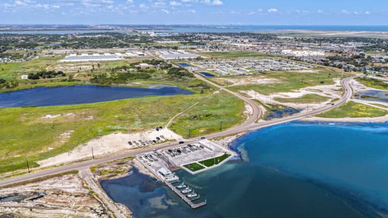 Lush waterfront park with boat docks, green spaces, and scenic lakes near urban development.