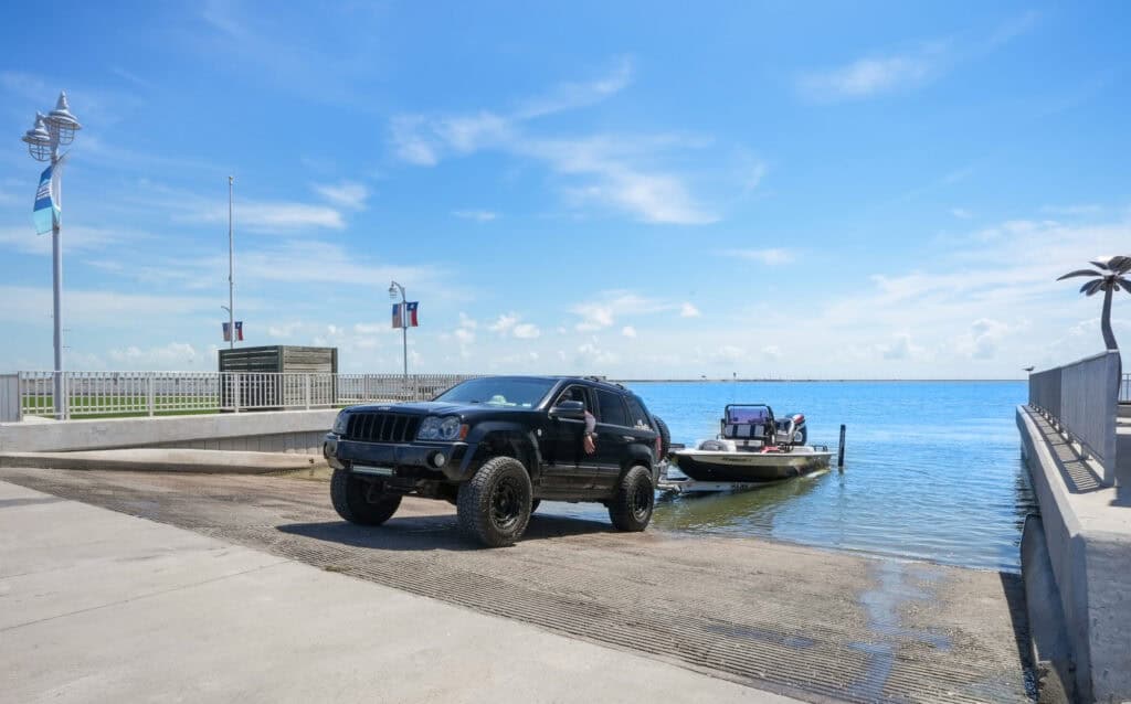 Outrig's Boat launch with truck backing a boar into the water on a clear day