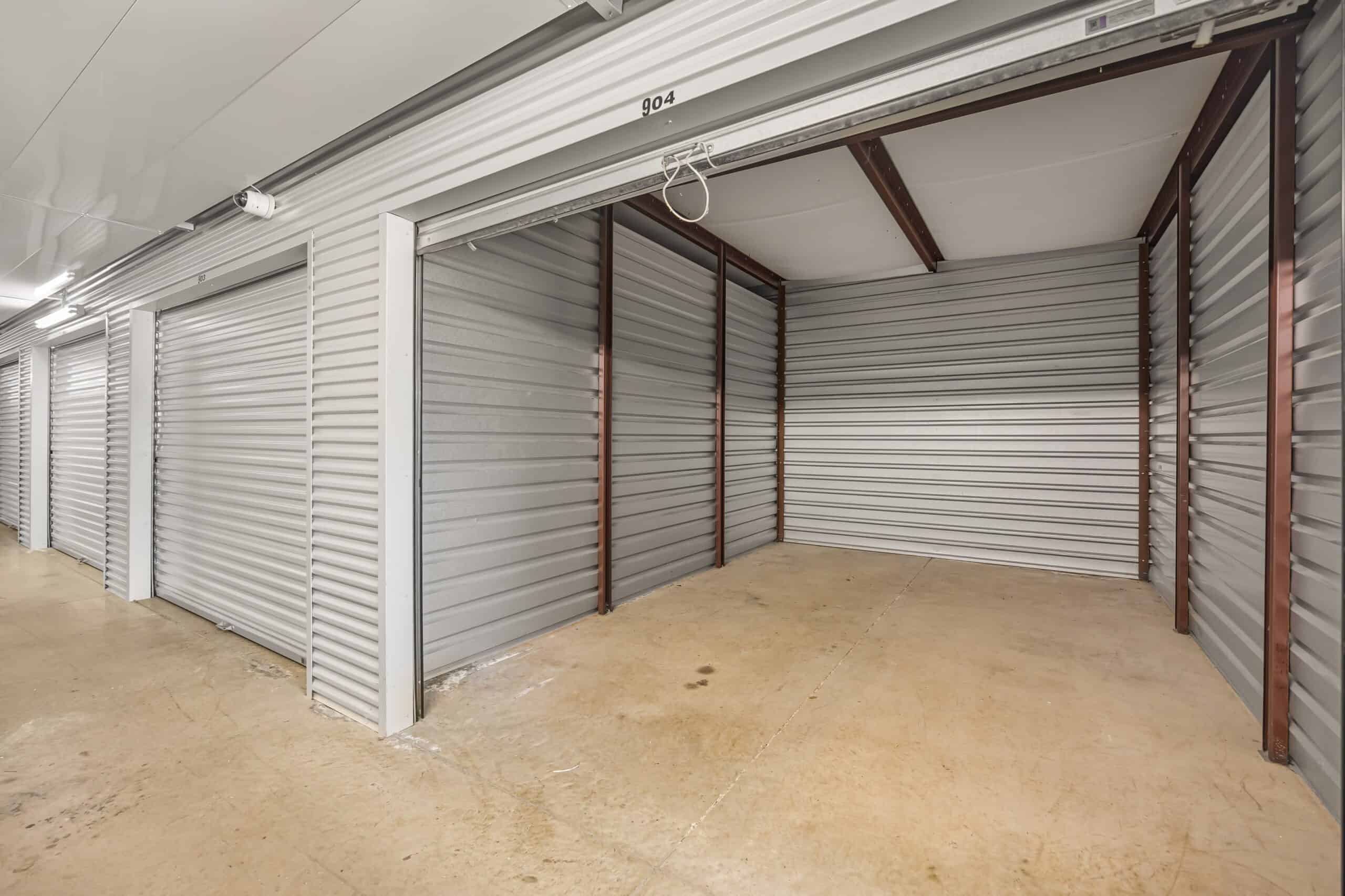 Lockable storage units with metal roll-up doors and concrete floors.