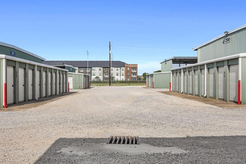 Outrig West 08252025-9-min Self-storage units in a secure outdoor storage facility with apartment buildings in the background.